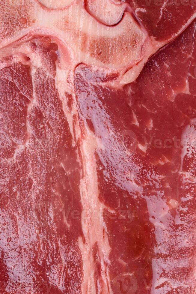 rå färsk saftig nötkött T ben biff med salt, kryddor och örter foto