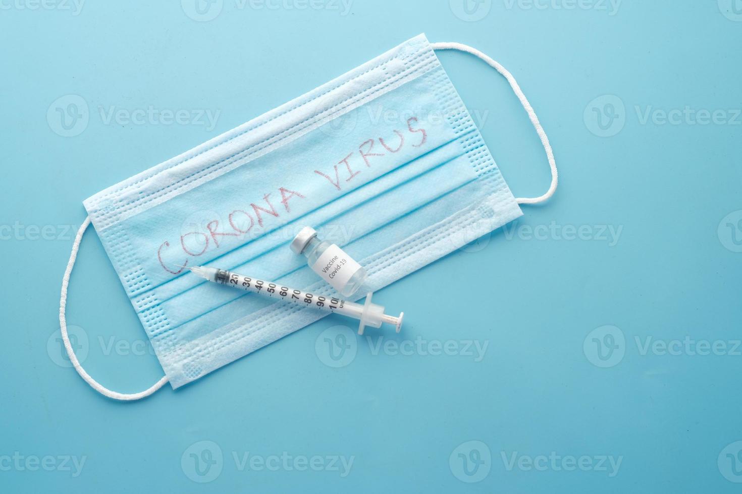 kirurgisk ansiktsmask, coronavirusvaccin och spruta på blå bakgrund foto