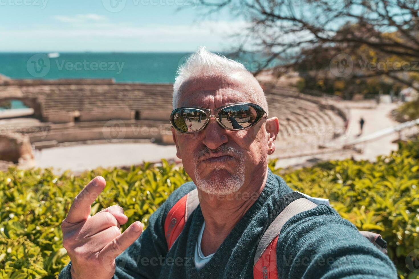 stilig mitten åldrig man besöker tarraco arkeologisk komplex, tarragona - Lycklig turist tar en selfie i främre av roman ruiner foto