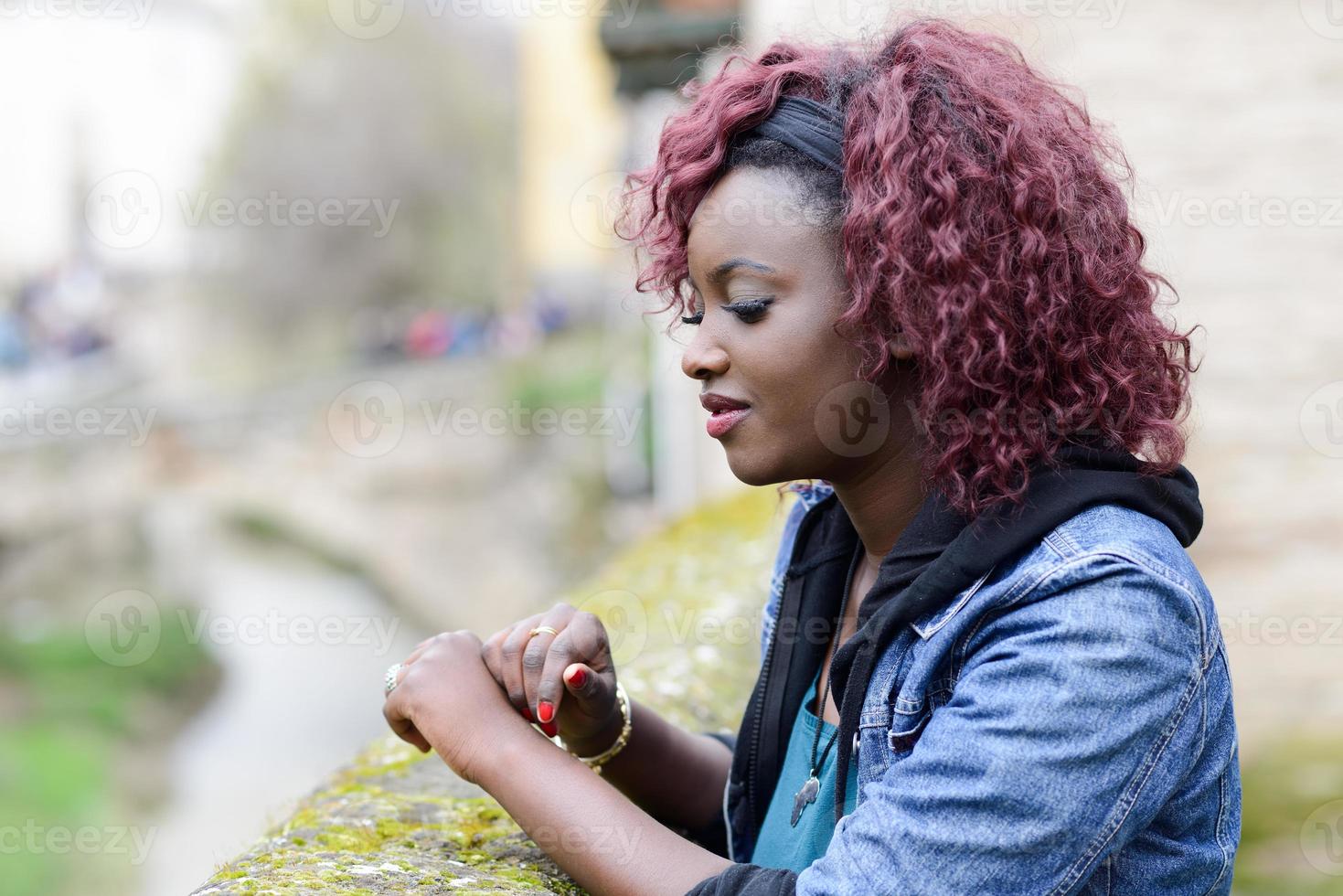 vacker svart kvinna i urban bakgrund med rött hår foto