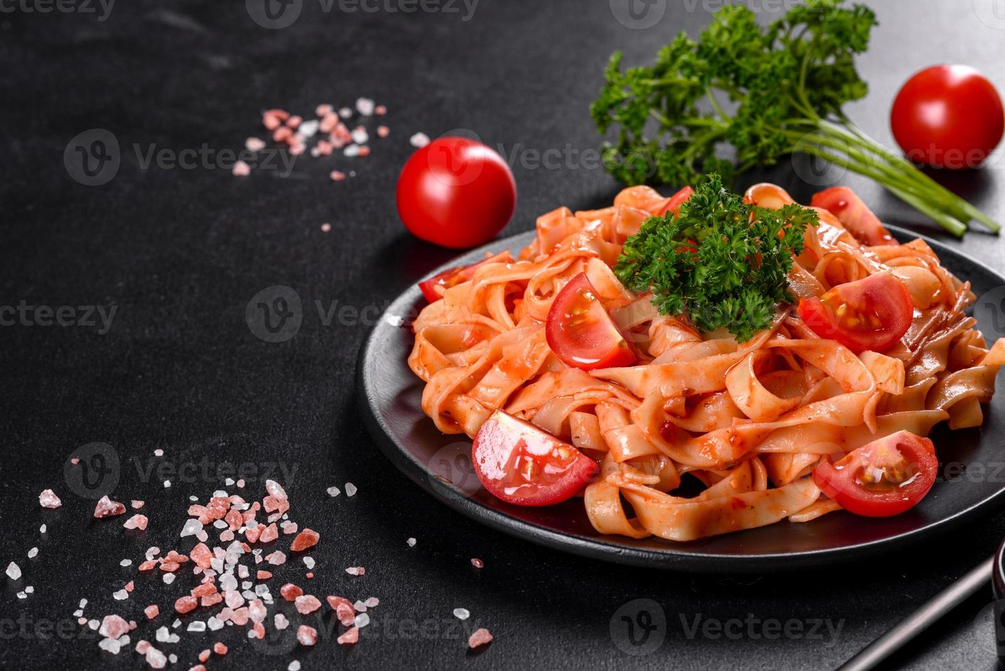 läcker färsk pasta med tomatsås med kryddor och örter på en mörk bakgrund foto