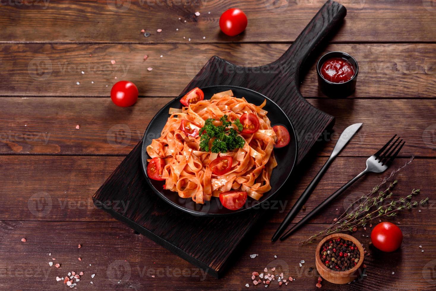 läcker färsk pasta med tomatsås med kryddor och örter på en mörk bakgrund foto