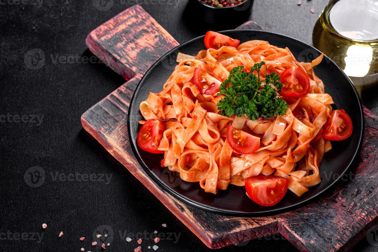 läcker färsk pasta med tomatsås med kryddor och örter på en mörk bakgrund foto