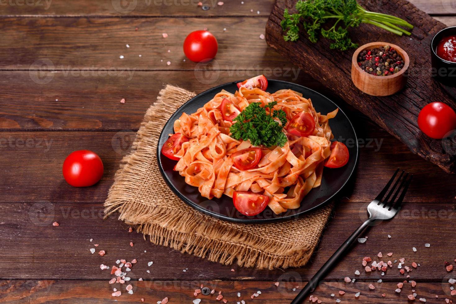 läcker färsk pasta med tomatsås med kryddor och örter på en mörk bakgrund foto