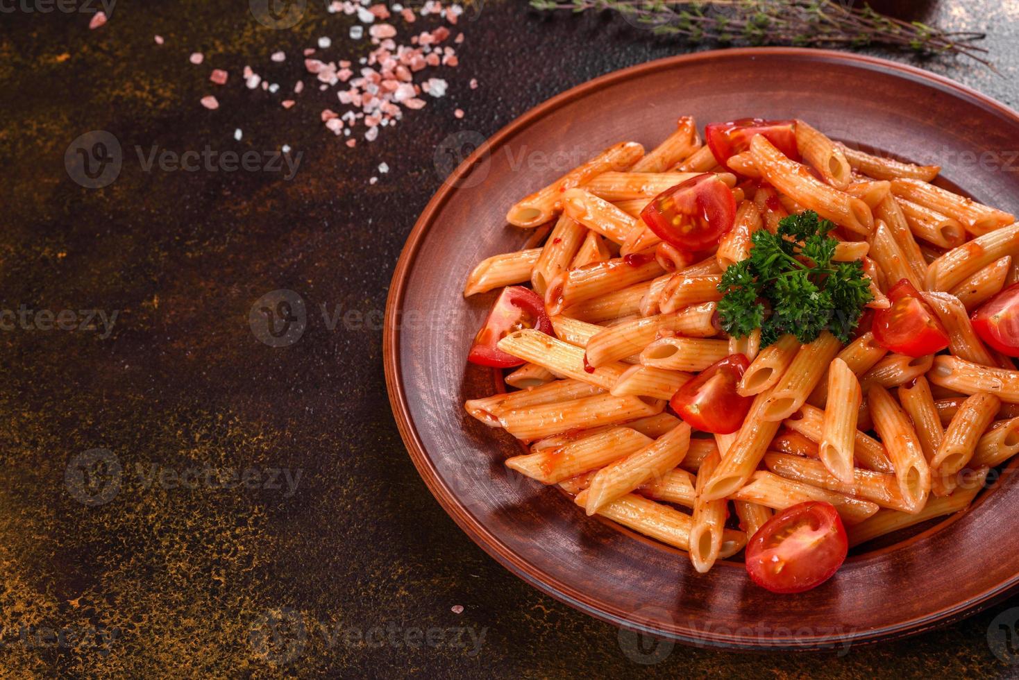 läcker färsk pasta med tomatsås med kryddor och örter på en mörk bakgrund foto