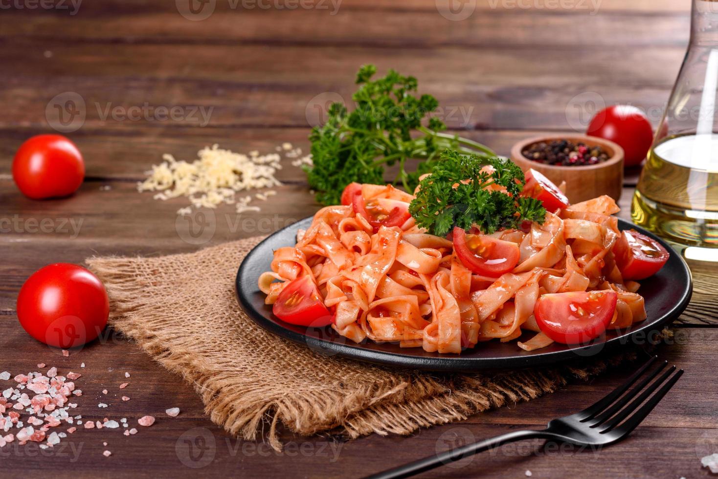 läcker färsk pasta med tomatsås med kryddor och örter på en mörk bakgrund foto