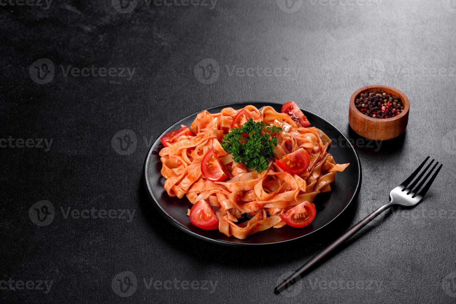 läcker färsk pasta med tomatsås med kryddor och örter på en mörk bakgrund foto