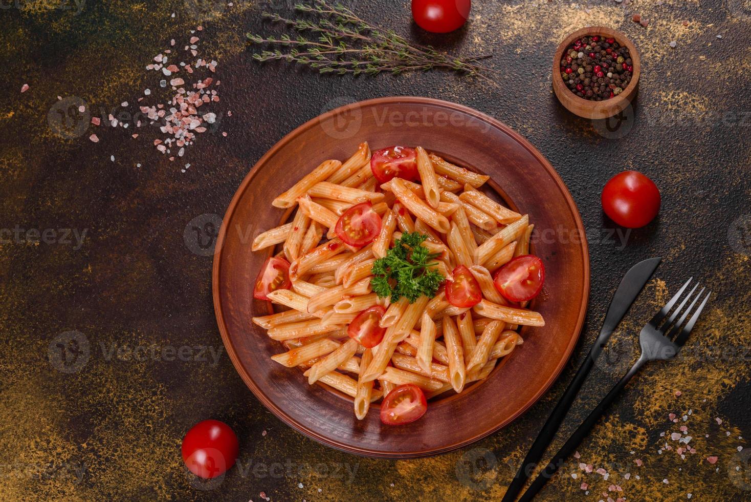 läcker färsk pasta med tomatsås med kryddor och örter på en mörk bakgrund foto