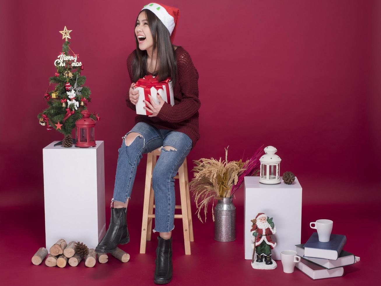 härlig jultomteflicka i studio på röd bakgrund, julkoncept foto