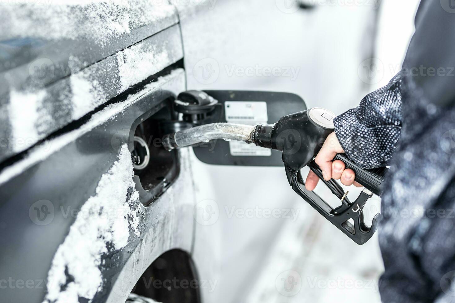 hand av en man fyllning upp de bränsle tank av hans bil under frysning snöig vinter- foto