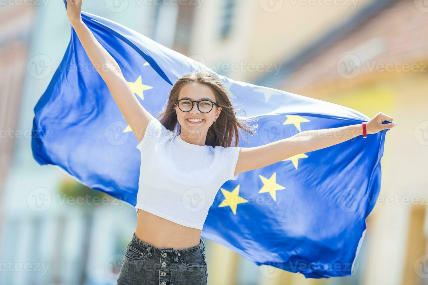 söt Lycklig ung flicka med de flagga av de europeisk union i de gator någonstans i Europa foto