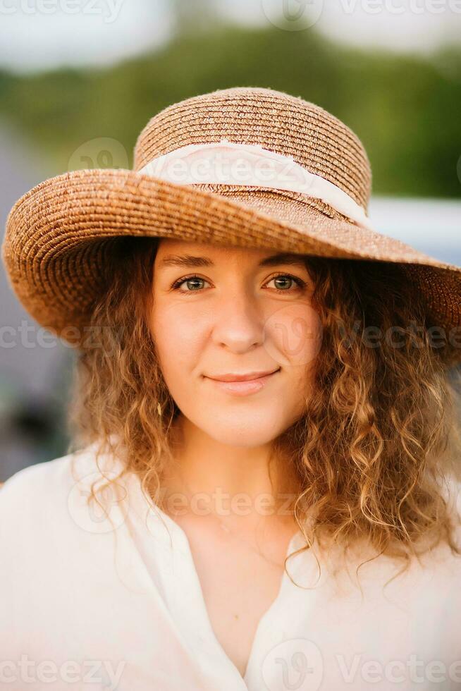 skön ung kvinna med lockigt hår med hatt. solnedgång eller soluppgång, ljus kväll ljus foto