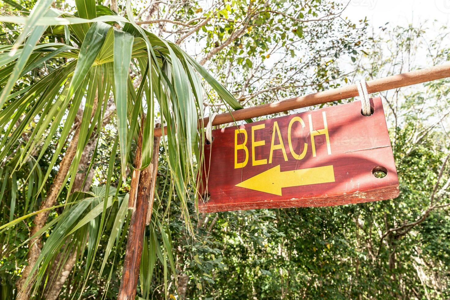 tecken ordspråk strand och ett pil pekande till de vänster dirigerar turister till de närmast havet i tropisk destination foto