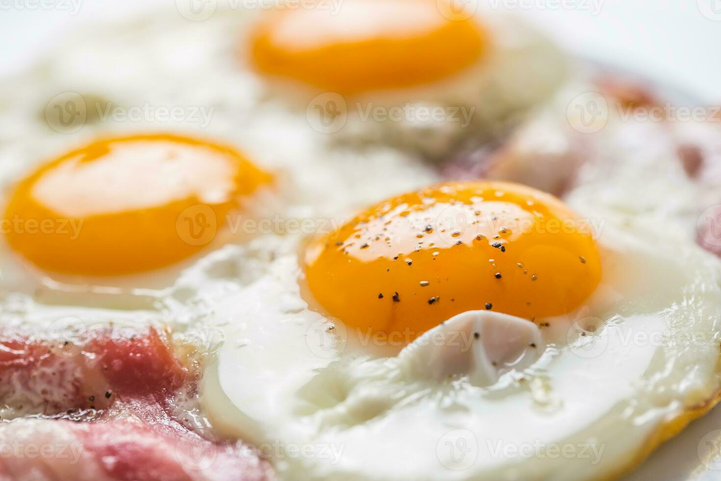 skinka och ägg. bacon och ägg. saltade ägg med peppar på vit tallrik. engelsk frukost foto