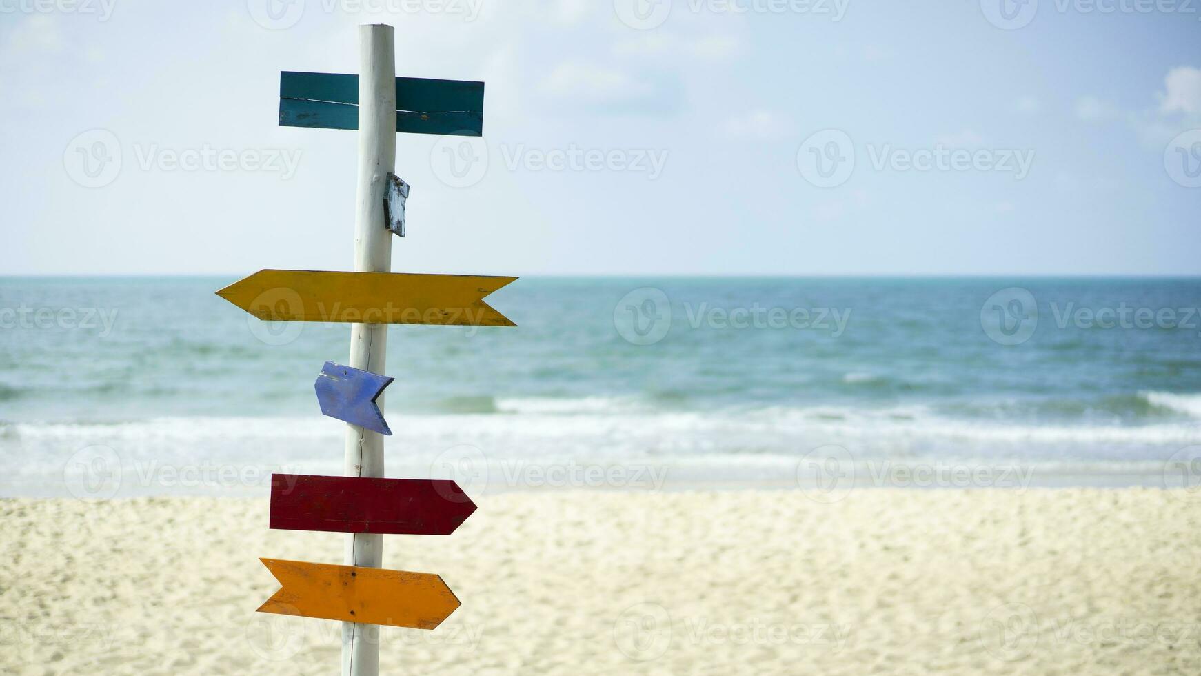 färgrik tömma tecken på sommar strand. tömma tecken pekande på en tropisk strand mot de bakgrund av de hav och vit sand strand. foto