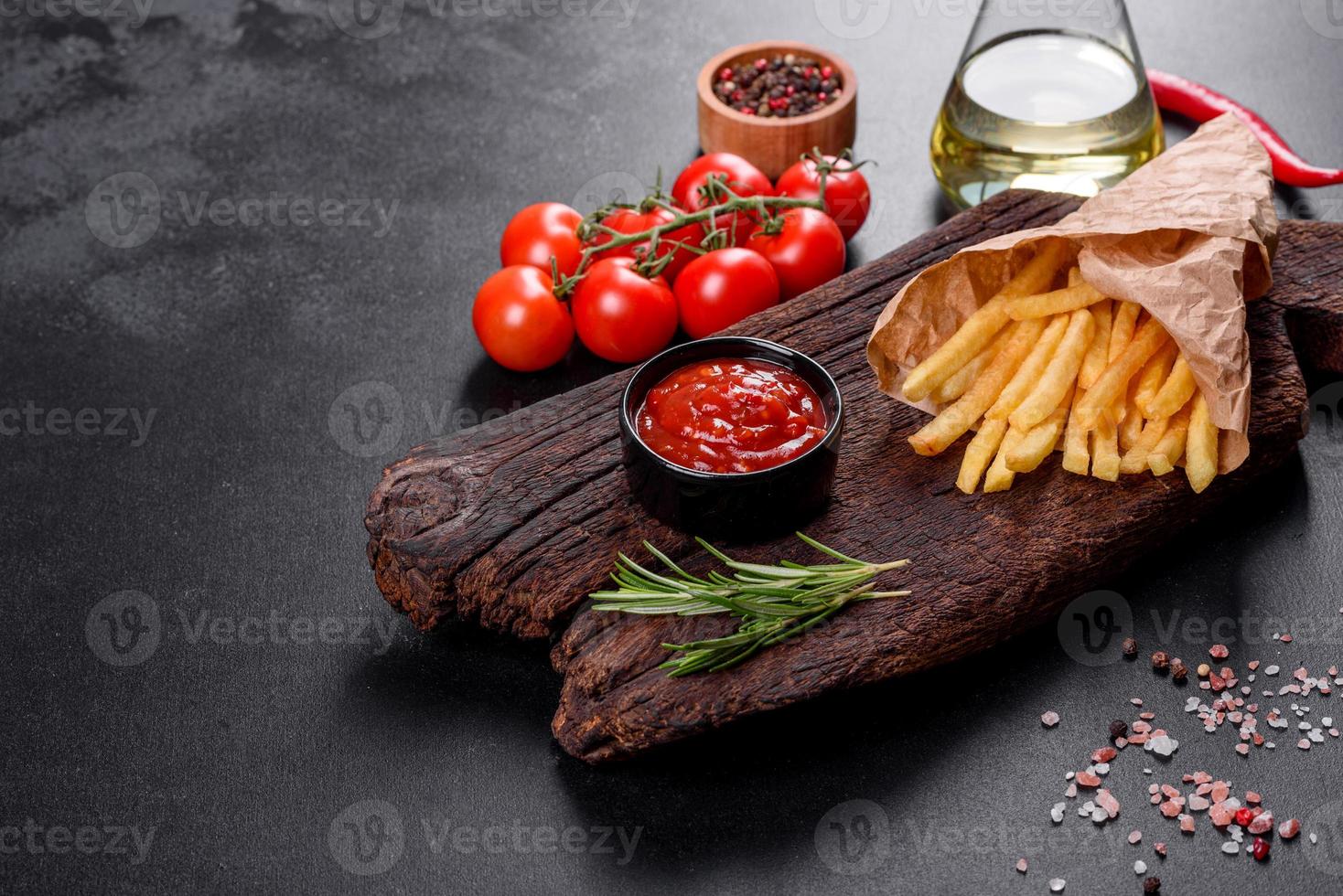 färska välsmakande pommes frites och röd sås på en träskärbräda foto