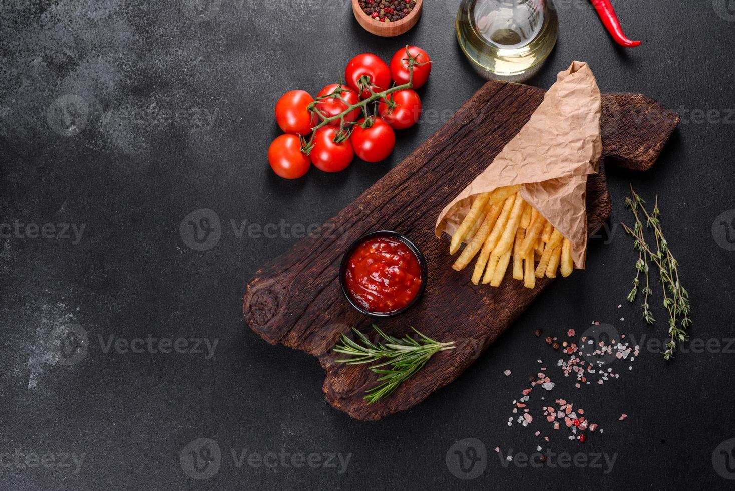 färska välsmakande pommes frites och röd sås på en träskärbräda foto