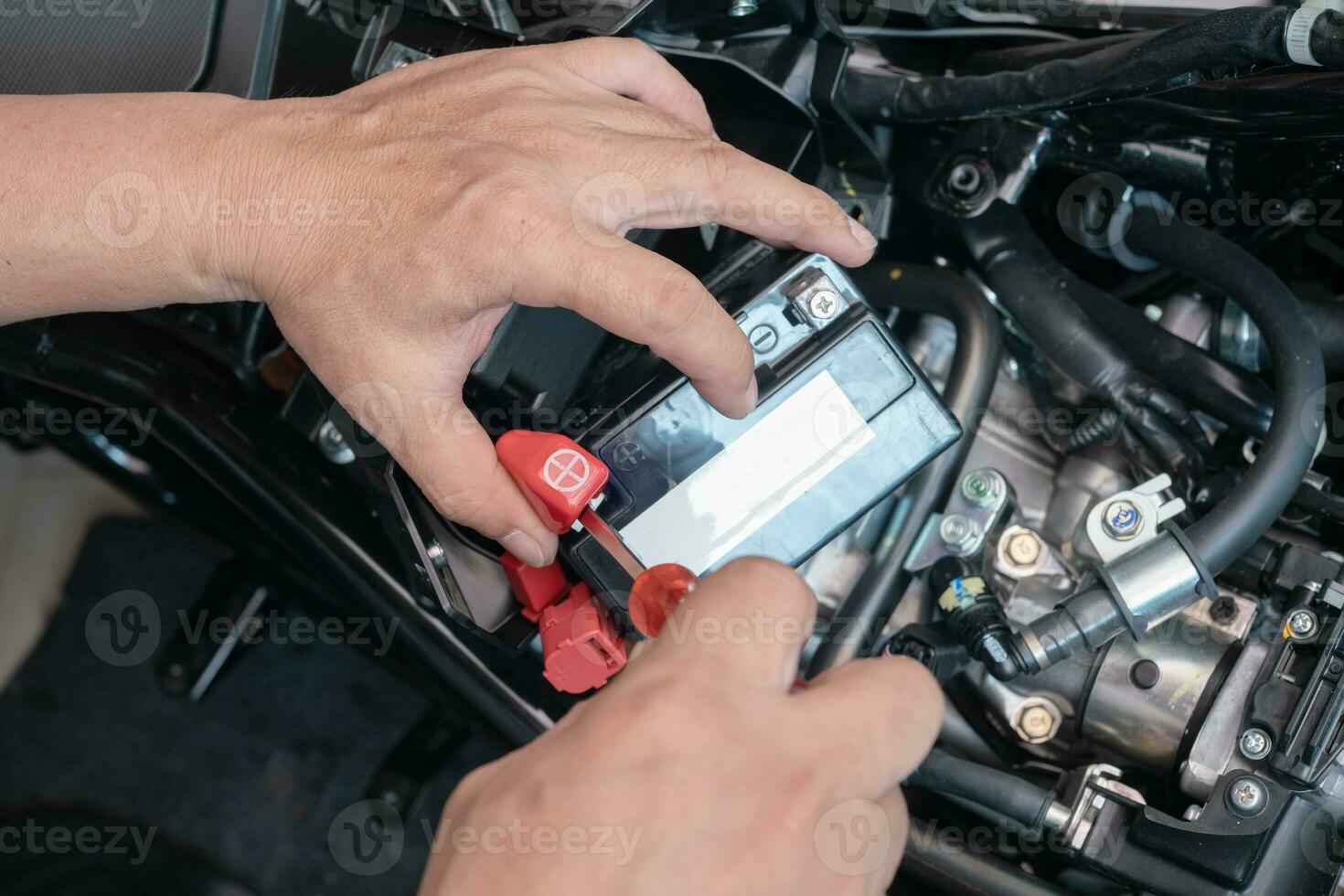 mekaniker ta bort de batteri terminal öppen med en skruvmejsel, och tar de batteri ut av de motorcykel till laddning, motorcykel underhåll och reparera begrepp . selektiv fokus foto