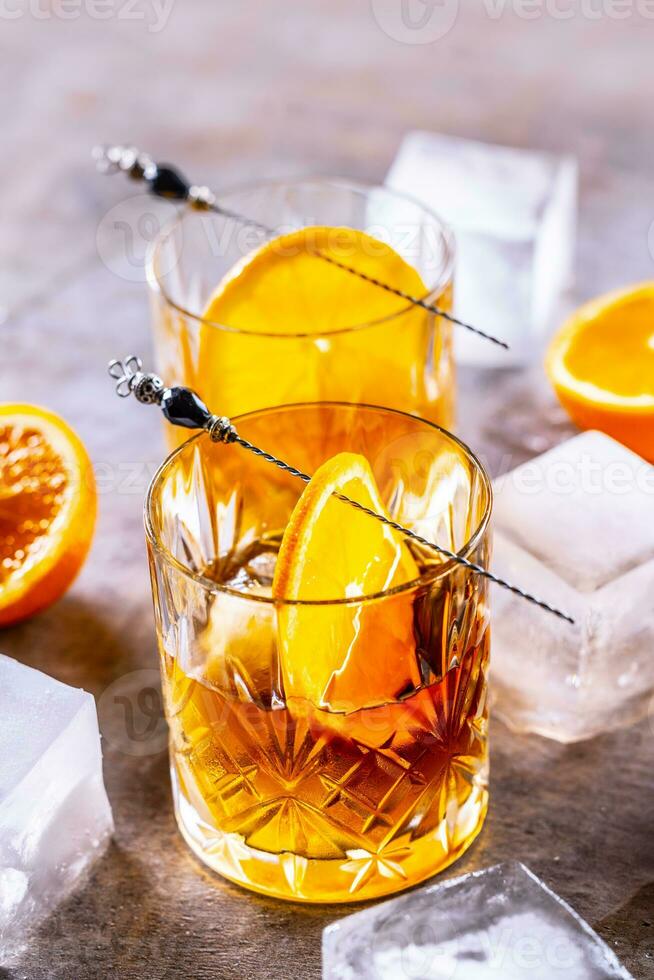 glasögon av cocktail drycker gammal fashioned med apelsiner och is kuber foto