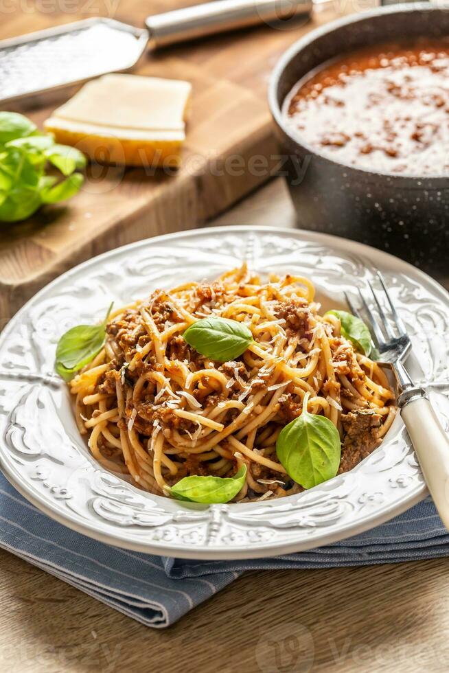 italiensk pasta spaghetti bolognese eras på vit tallrik med parmesan ost och basilika foto