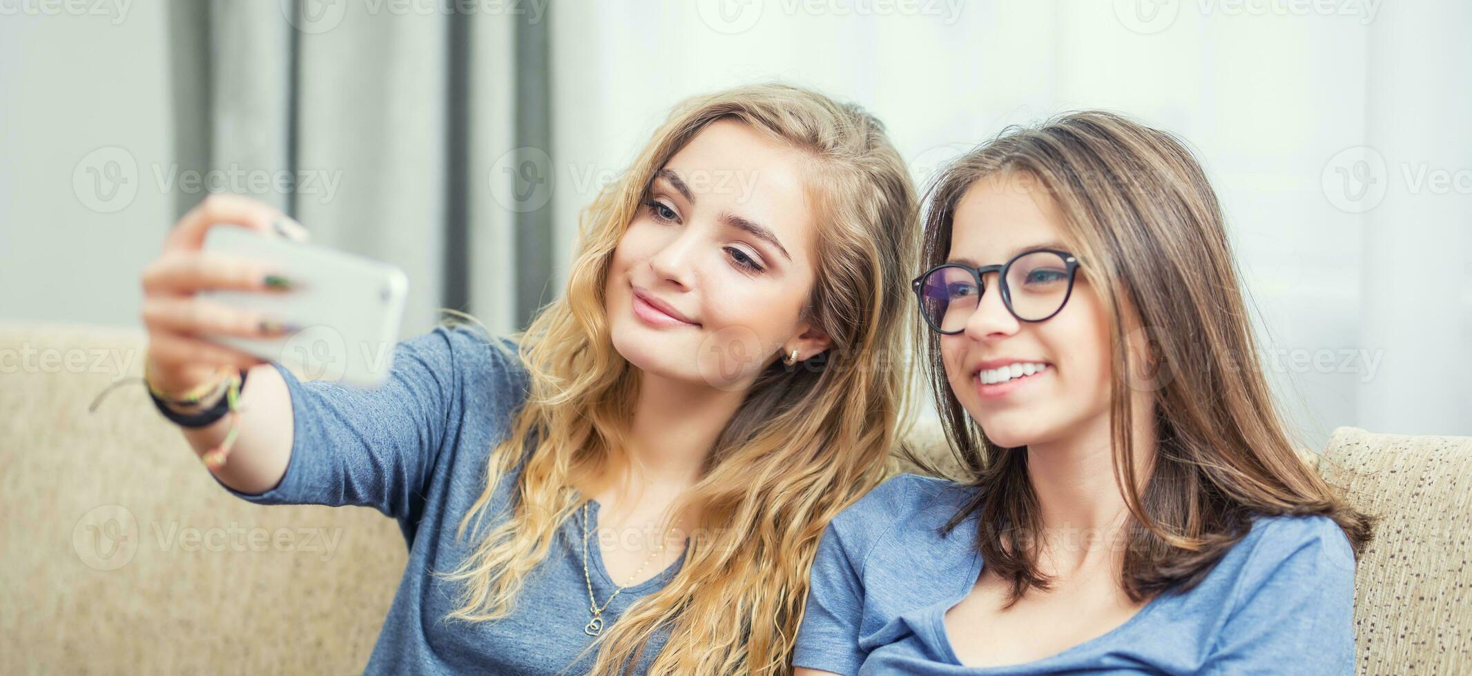 två tonåring flickor leende och ta en selfie tillsammans. foto