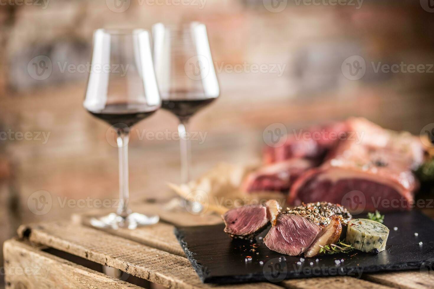 två koppar med röd vin rostad och rå nötkött biff på skiffer styrelse foto