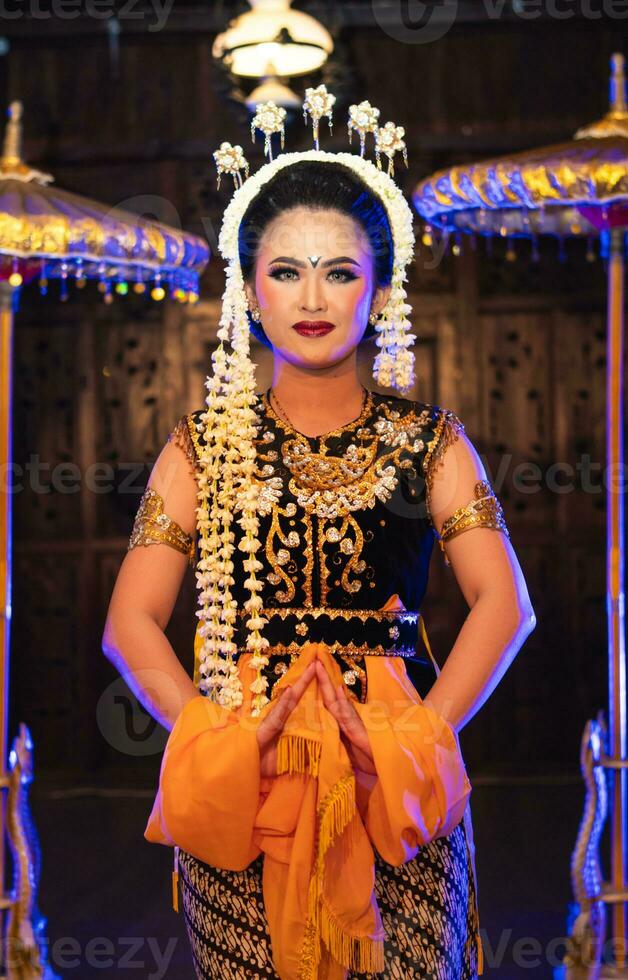 en javanese dansare danser i en gyllene kostym och en gul sjal på skede foto