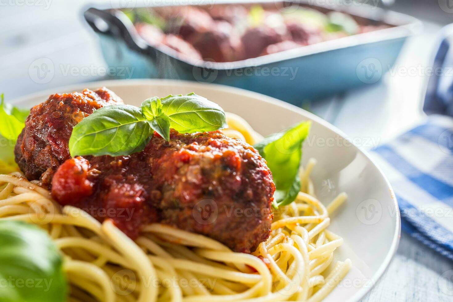 läcker italiensk måltid kött nötkött bollar med pasta spaghetti och basilika i vit tallrik. foto