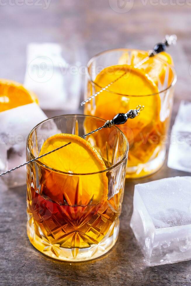 glasögon av cocktail drycker gammal fashioned med apelsiner och is kuber foto
