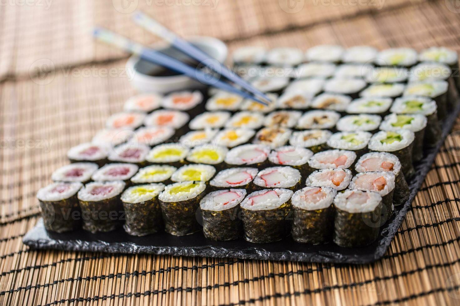 samling av sushi maki på skiffer styrelse med soja sås och ätpinnar foto