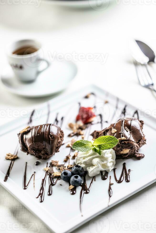 choklad efterrätt med vispad grädde, mynta och bär dekoration och en kopp av italiensk espresso på de sida foto