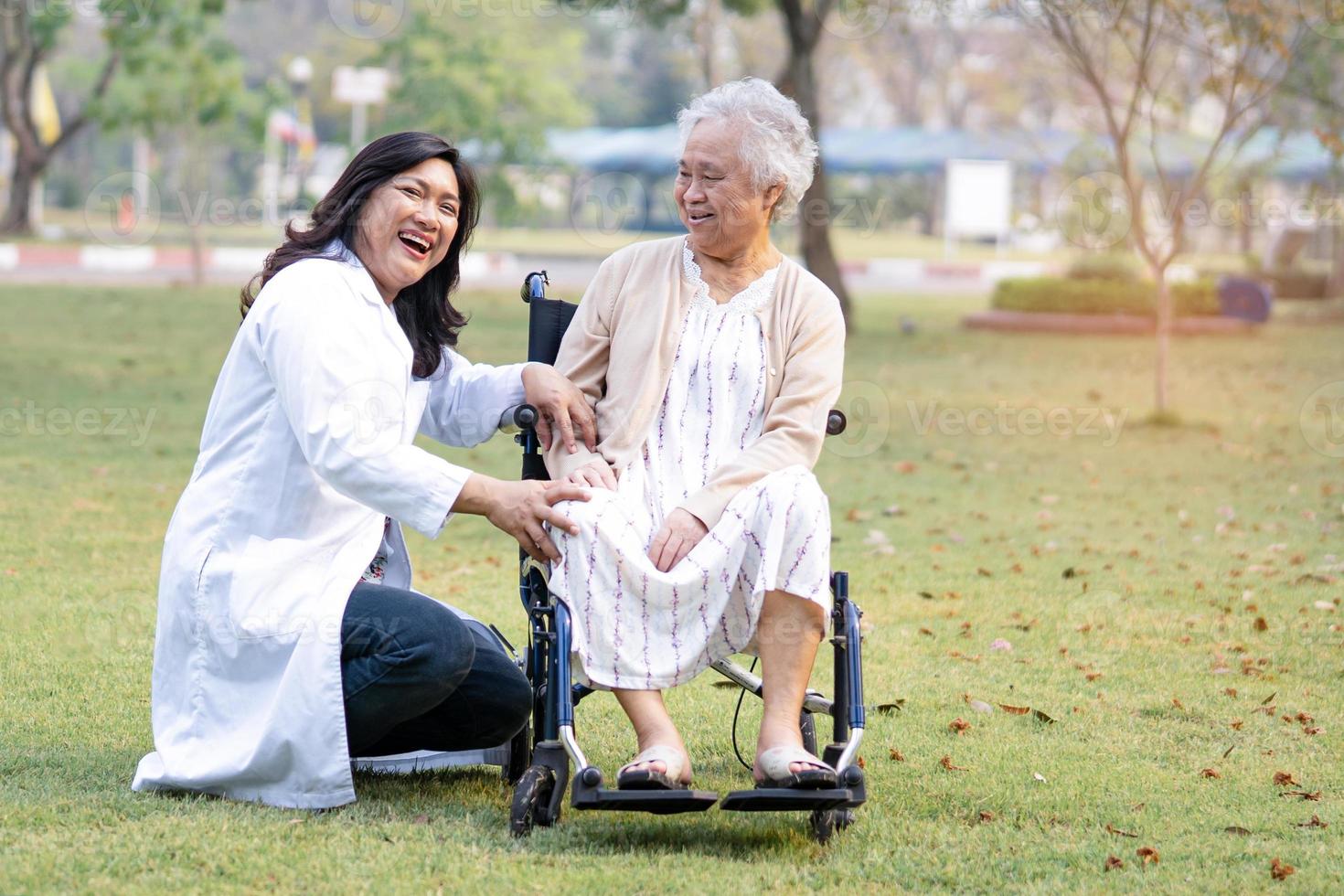 läkare hjälp och vård asiatiska senior eller äldre gammal dam kvinna patient sitter på rullstol på park i vårdsjukhus avdelning hälsosamma starka medicinska koncept foto