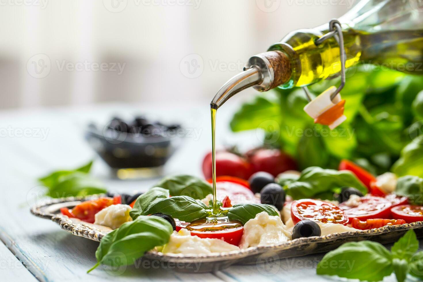 häller oliv olja på caprese sallad. friska italiensk eller medelhavs måltid foto