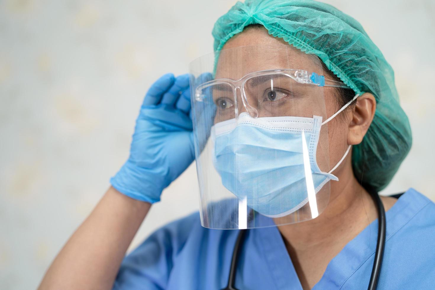 asiatisk läkare som bär ansiktsskydd och folkdräkt nytt normalt för att kontrollera patientens skydd infektion covid-19 koronavirusutbrott vid karantän vårdavdelningen. foto