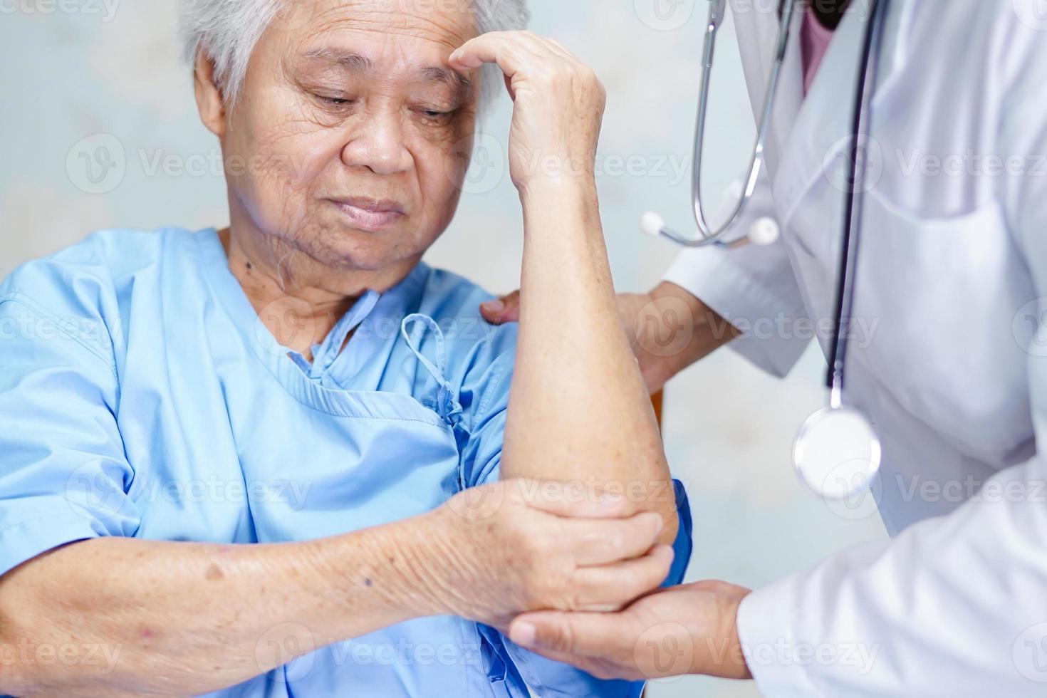 asiatisk senior eller äldre gammal damkvinnapatient känner smärta hennes armbåge på sängen på vårdavdelningen, hälsosamt starkt medicinskt koncept. foto