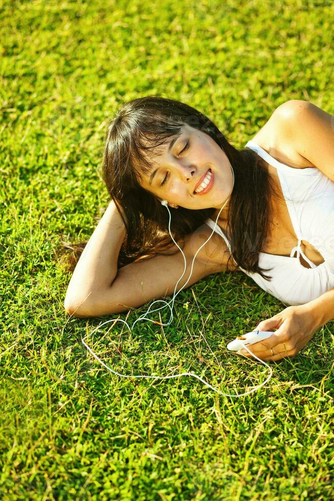 en kvinna om på de gräs lyssnande till musik foto