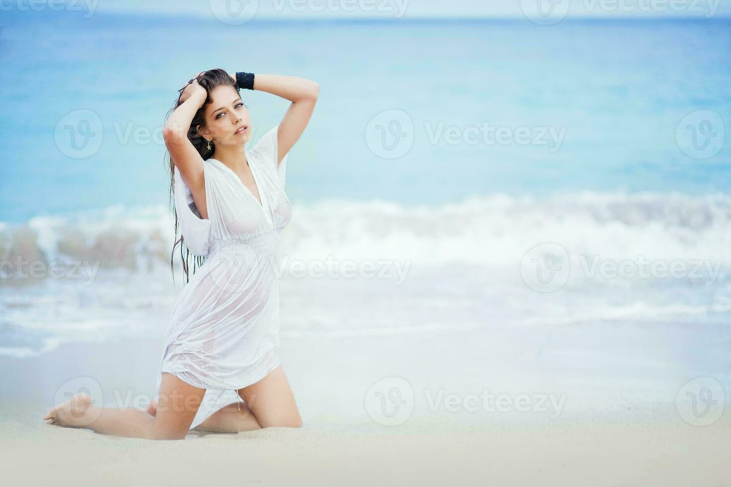 en kvinna i en vit klänning Sammanträde på de strand foto