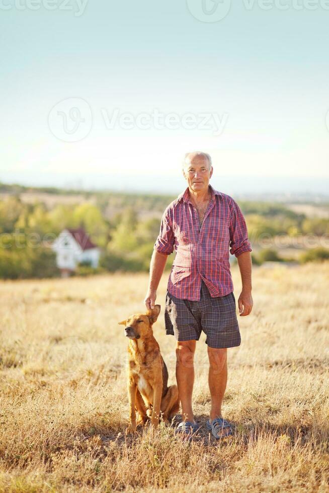 ett äldre man och hans hund i en fält foto