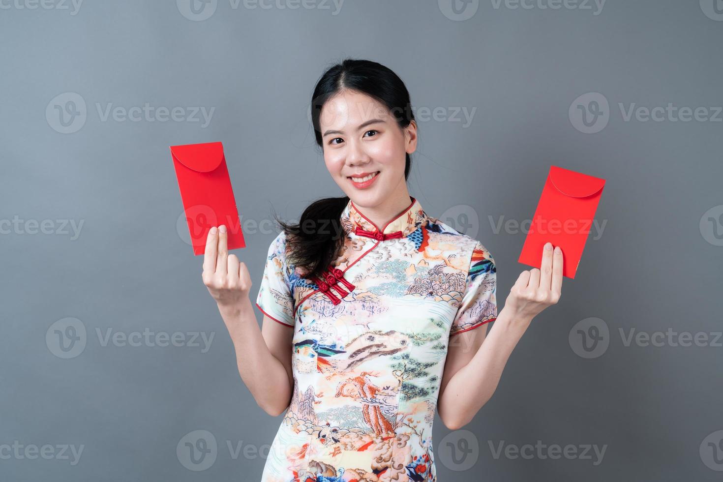 asiatisk kvinna bär kinesisk traditionell klänning med rött kuvert eller rött paket foto