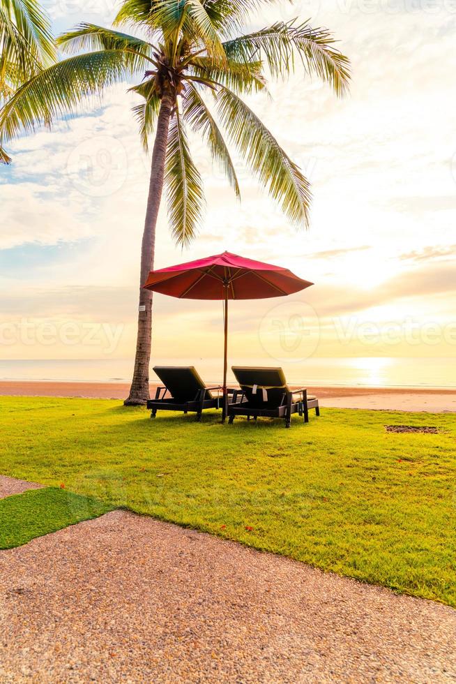 paraply med stol med havsstrandbakgrund och soluppgång på morgonen foto
