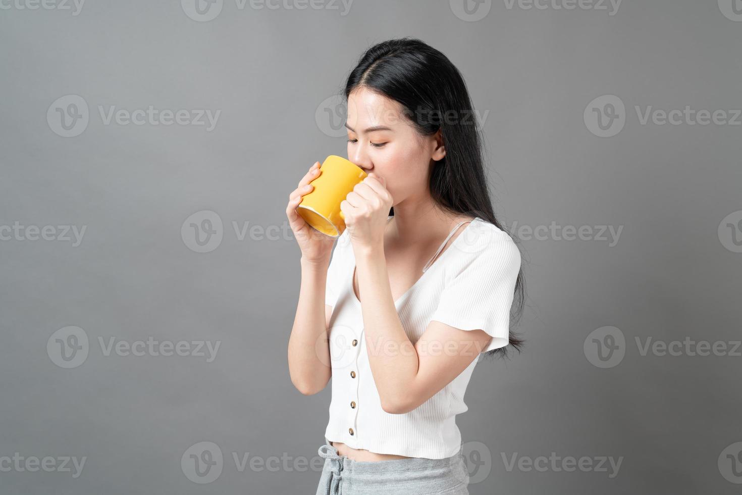 ung asiatisk kvinna med lyckligt ansikte och hand som håller kaffekoppen foto