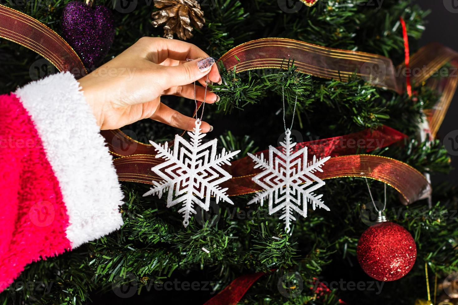 hand som håller julprydnaden framför julgranen foto