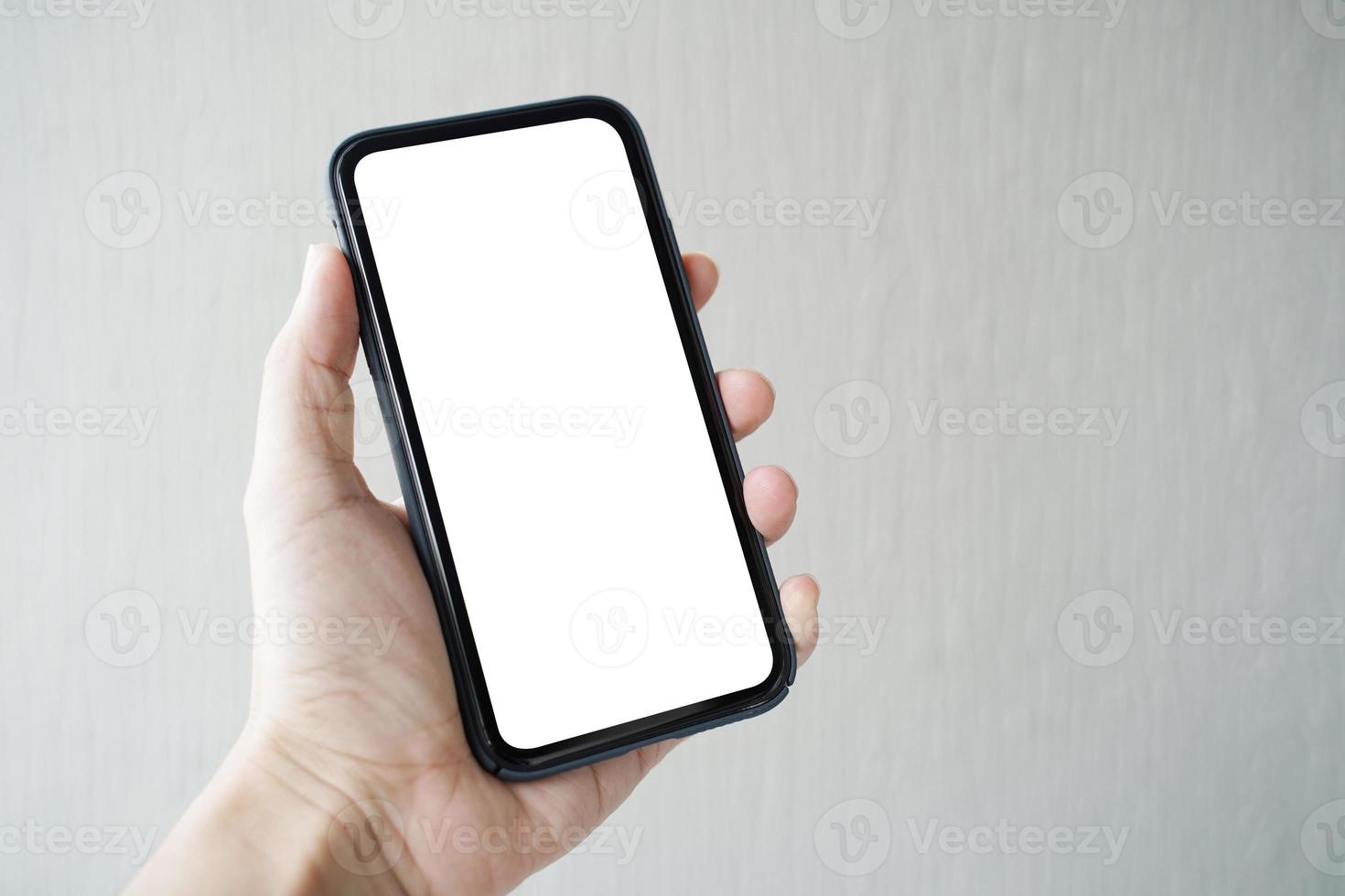 man handen håller smartphone med blank skärm på grå bakgrund, närbild av handen. utrymme för text. foto