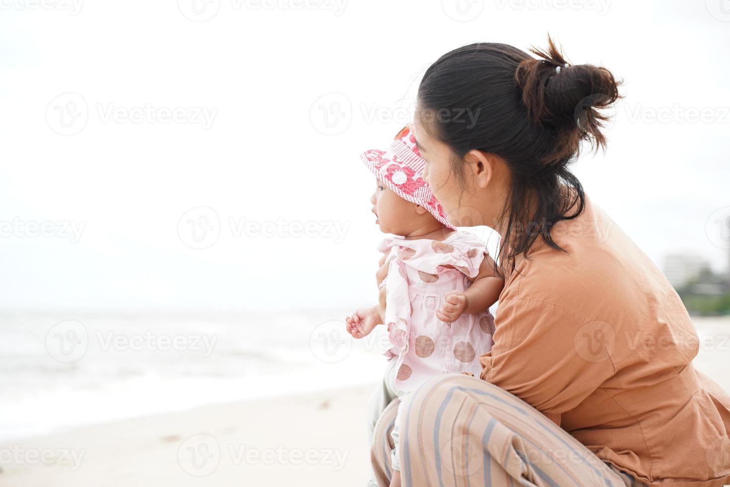 mor och baby dotter njuter på stranden. vacker familjesemester sommarsemester. foto