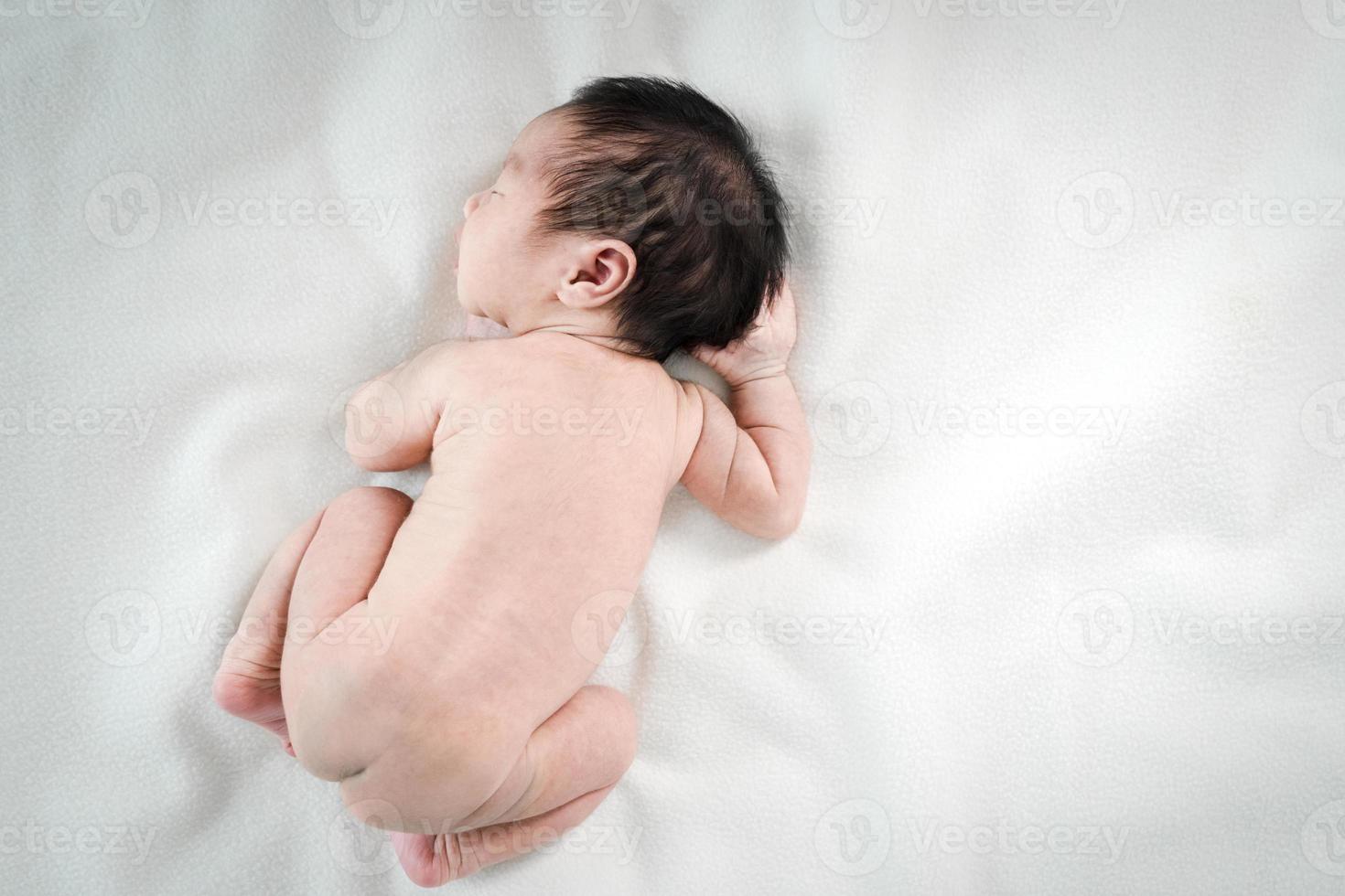 asiatisk nyfödd bebis som ligger sovande på vit filt. foto