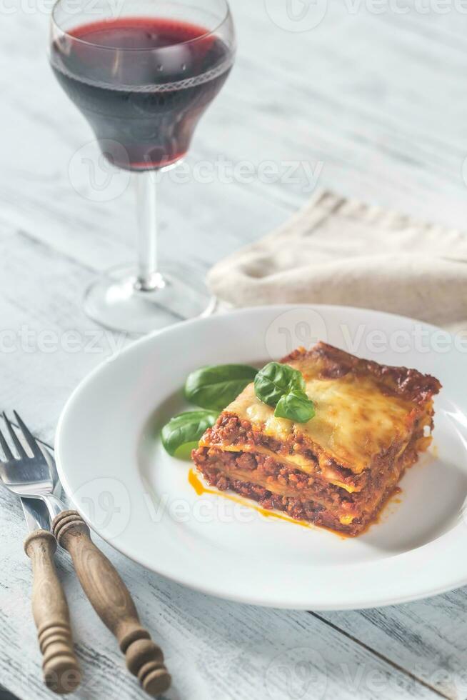 del av lasagne med en glas av vin på de trä- tabell foto