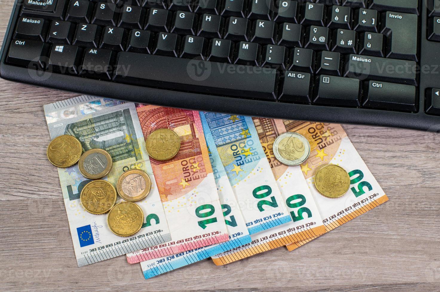 europengar av olika valörer och datorns tangentbord foto