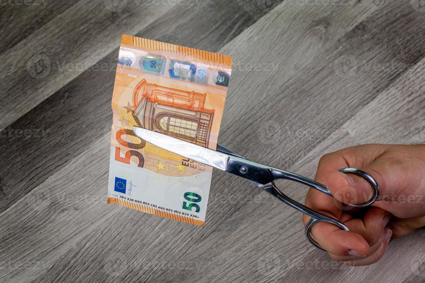 man skär 50 eurosedlar med sax foto