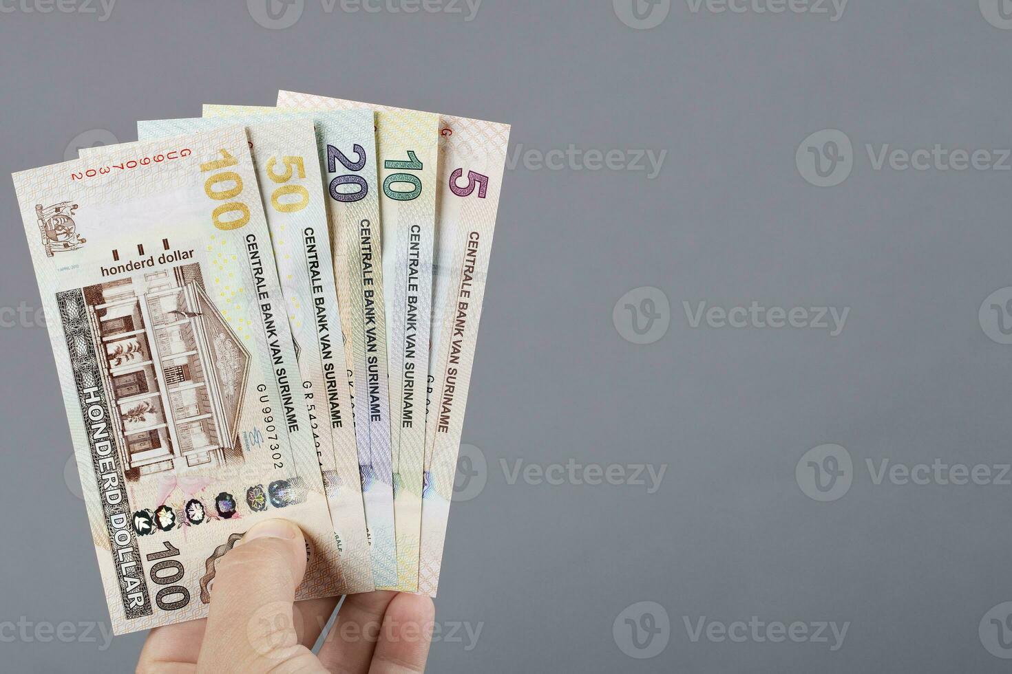 surinamiska pengar i de hand på en grå bakgrund foto