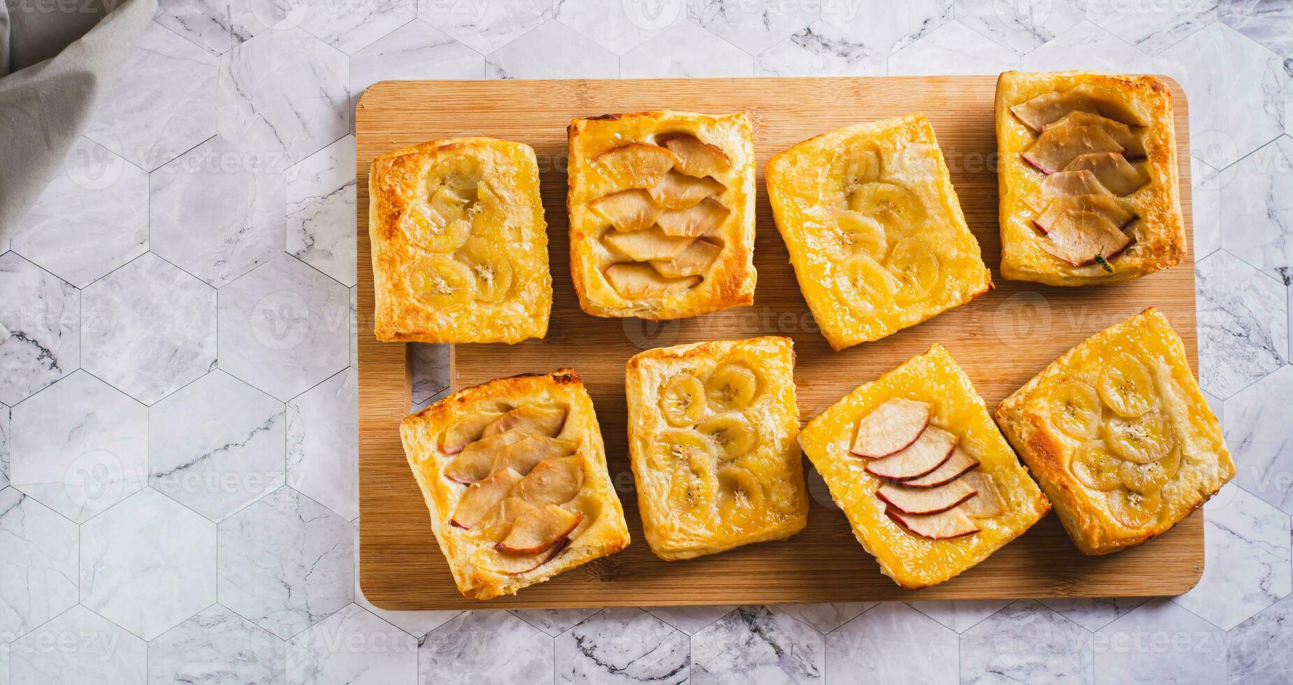 små upp och ner puff bakverk kakor med banan och äpple på en styrelse topp se webb baner foto